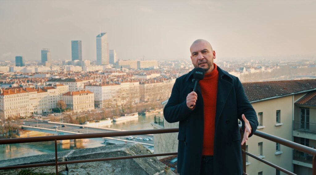 Grégory Fiori, fondateur de X-Pression Média, micro à la main avec la skyline de Lyon en arrière-plan