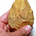 Biface acheuleen tenu a la main, outil prehistorique en pierre taillee