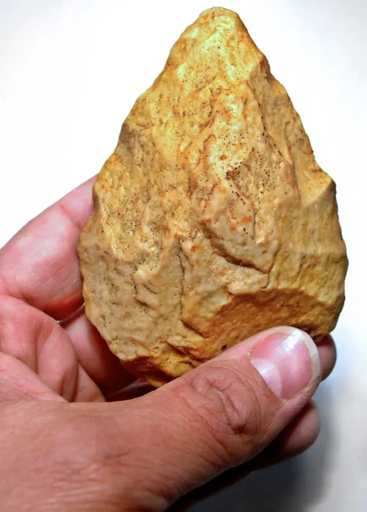 Biface acheuleen tenu a la main, outil prehistorique en pierre taillee