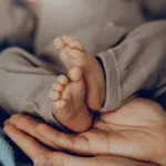 Pieds d'un nouveau-né tenus dans les mains d'un adulte