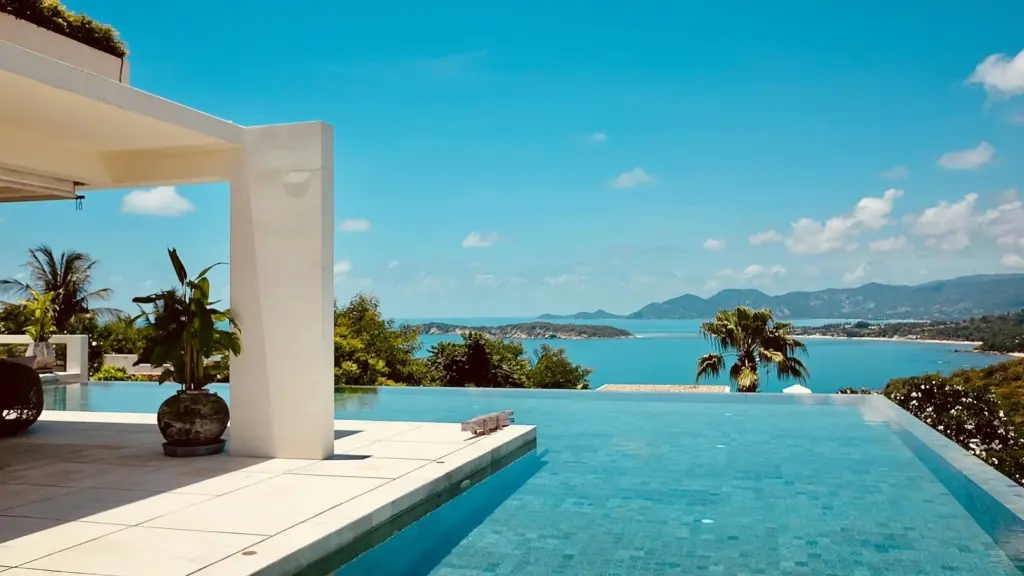 Piscine à débordement d'une villa surplombant une baie tropicale, illustration
