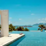 Piscine à débordement d'une villa surplombant une baie tropicale, illustration