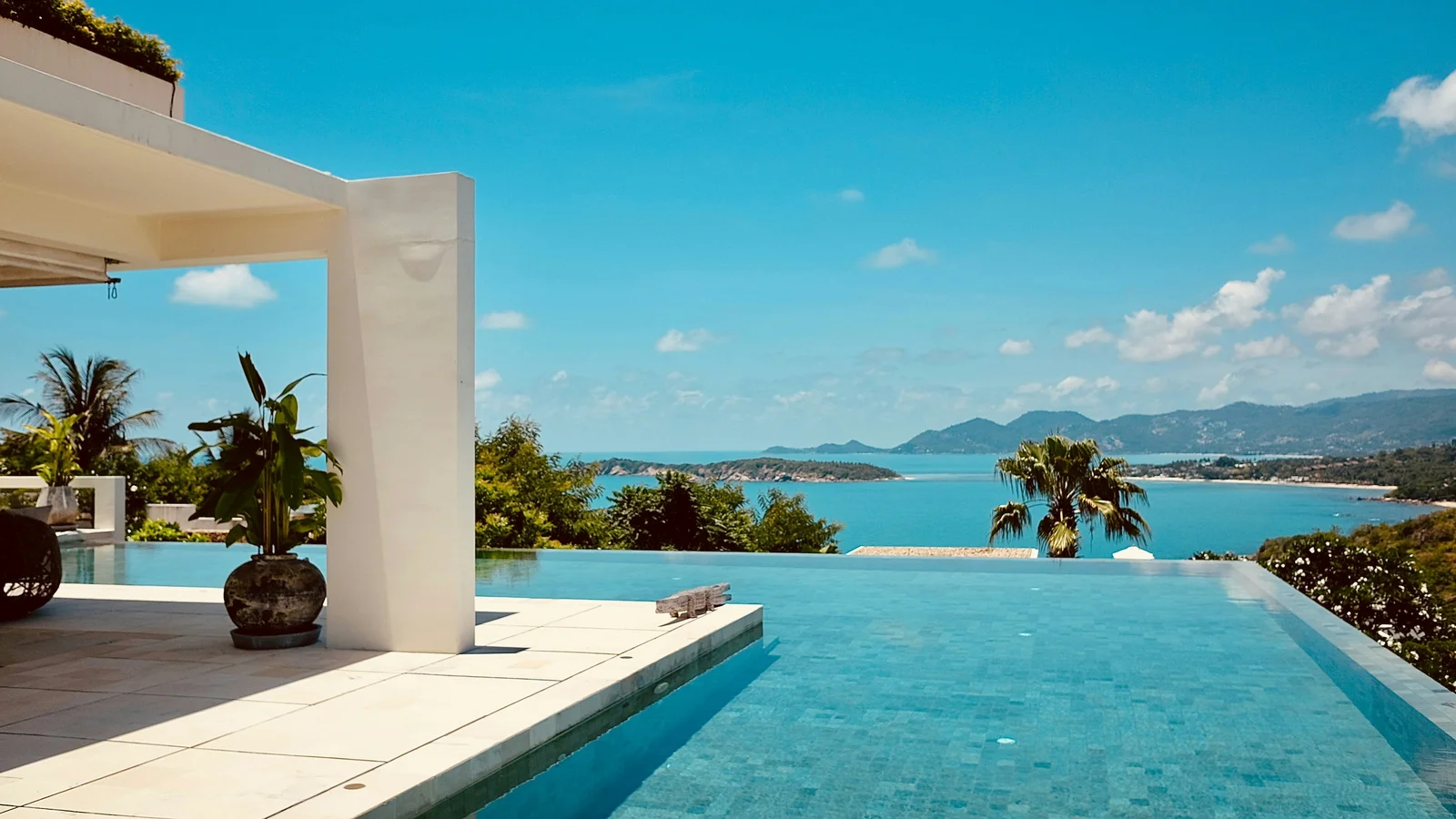 Piscine à débordement d'une villa surplombant une baie tropicale, illustration