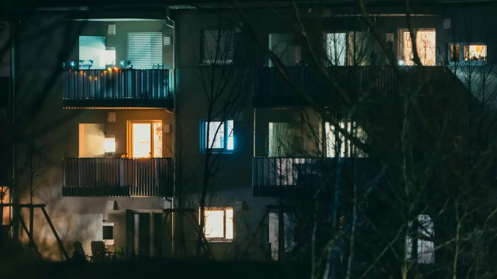 Façade d'un immeuble d'habitation aux fenêtres éclairées à la tombée de la nuit, illustration