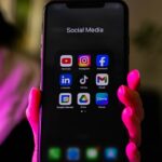 Smartphone affichant un dossier d'applications de réseaux sociaux, illustration de l'EU Kids Act