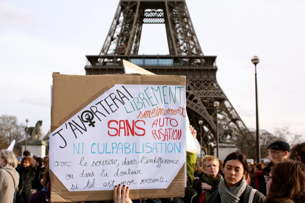 man in black jacket holding blue and white signage