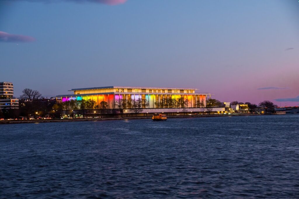 a large building is lit up at night by the water