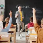 Enseignant interagissant avec des élèves qui lèvent la main en classe