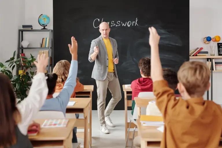 Enseignant interagissant avec des élèves qui lèvent la main en classe