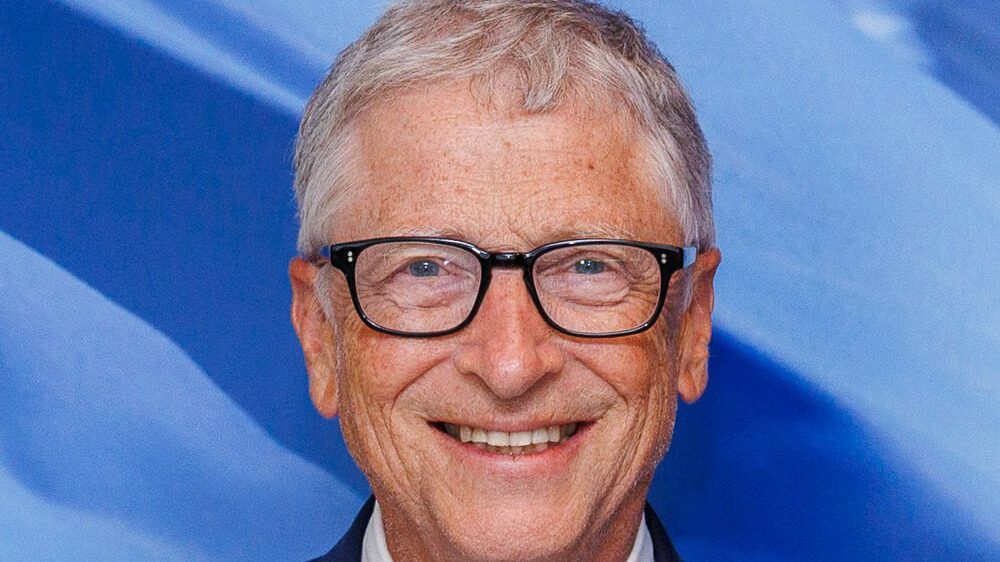 Portrait souriant de Bill Gates en costume, cadré en 16:9