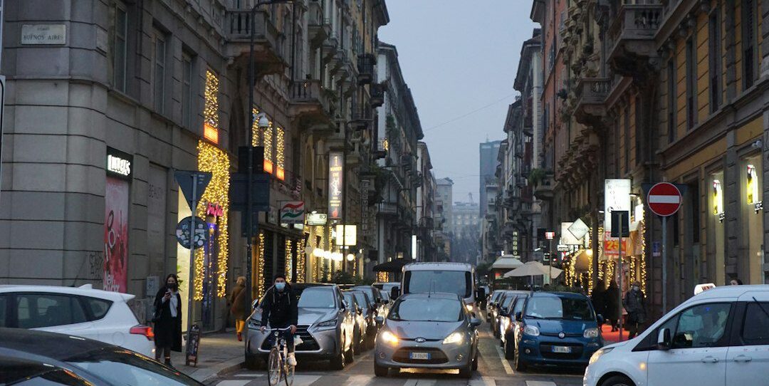 cars parked on street in between high rise buildings during daytime